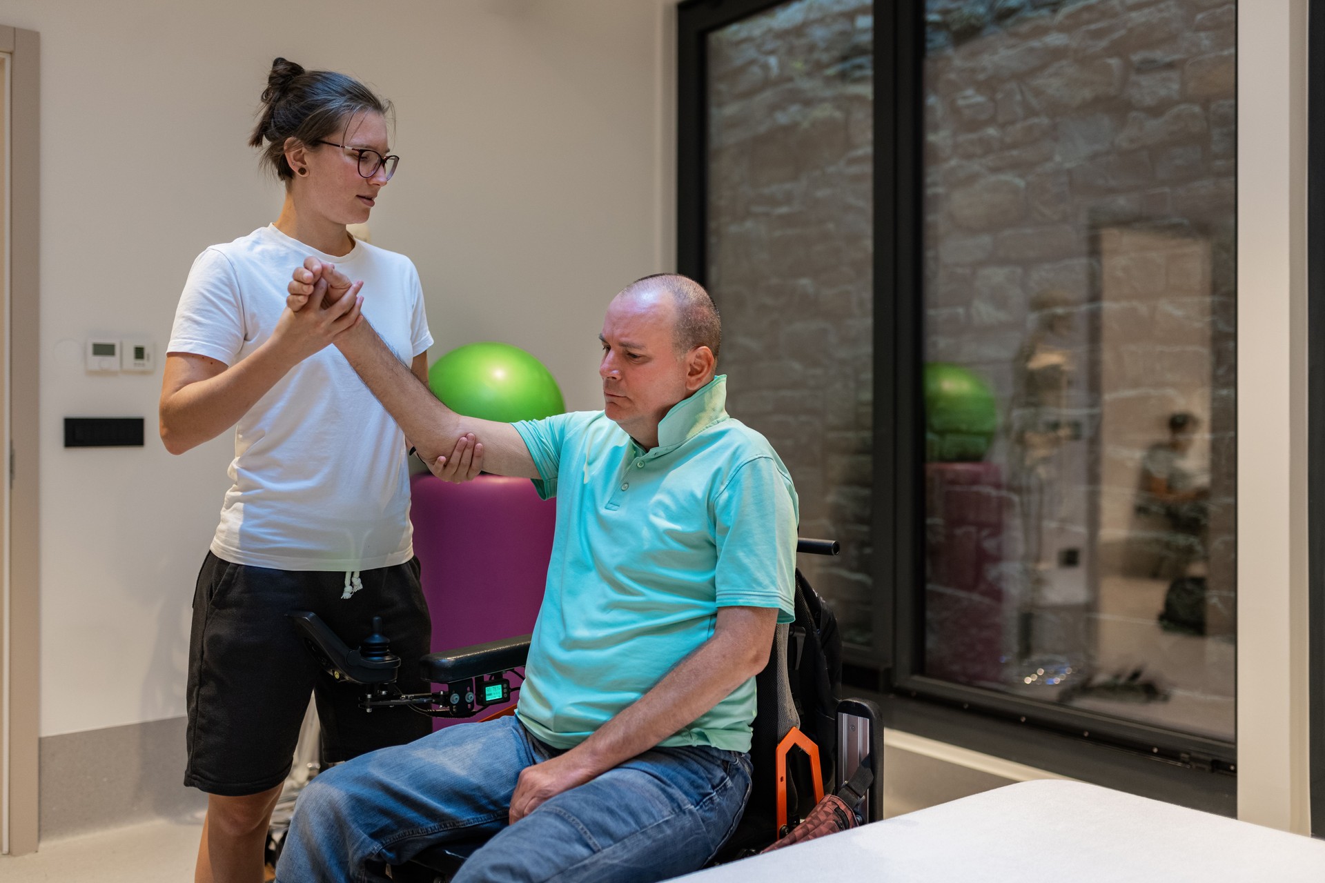 A disabled person with a physiotherapist at a physiatry rehabilitation office